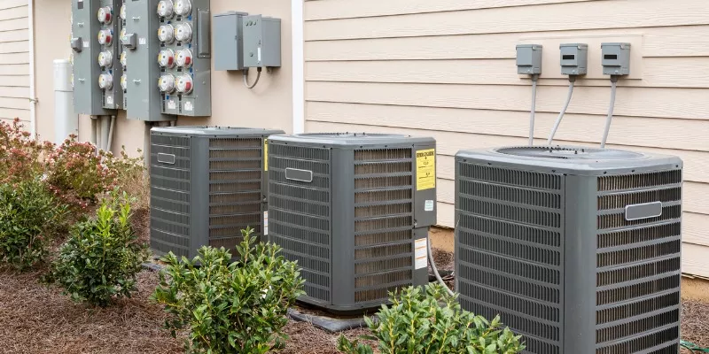three air conditioner units lined against side of house