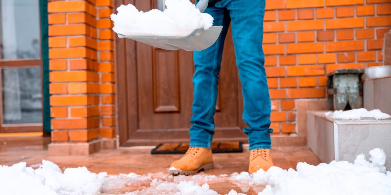 Man shoveling front entrance of home