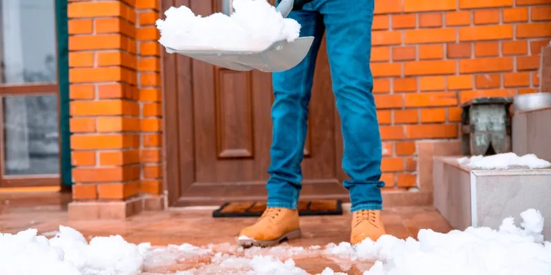 Man shoveling front entrance of home