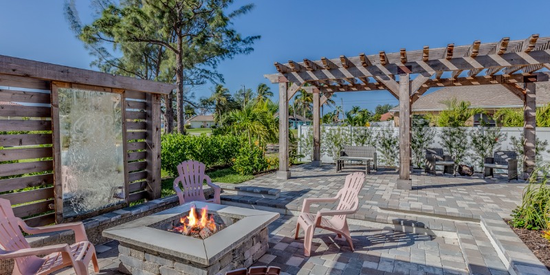 backyard patio with interlocking pavers furniture fireplace and pergola